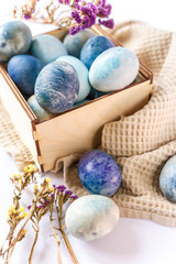 Easter colored eggs in a wooden box on white background. Easter eggs and spring flowers. Holiday pattern.