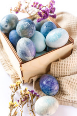 Easter colored eggs in a wooden box on white background. Easter eggs and spring flowers. Holiday pattern.