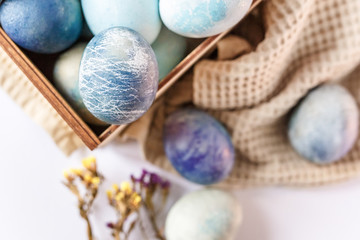 Easter colored eggs in a wooden box on white background. Easter eggs and spring flowers. Holiday pattern.