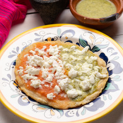 Mexican memela with green and red sauce on white background