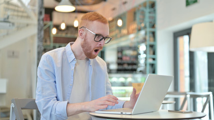 Shocked Expression by Redhead Man using Laptop in Cafe