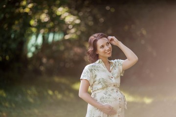 Portrait of a beautiful young pregnant woman in eco dress. Motherhood. A family. Summer.