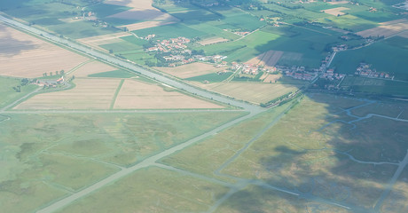 Aerial view from the plane over cities, with roads, river, forests, meadows, rural fields