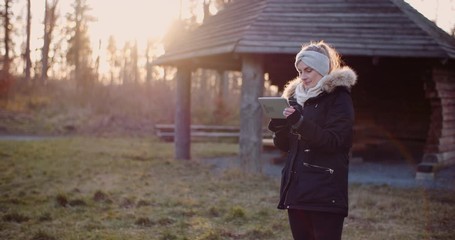 Wireless Technology - woman using digital tablet in park in autumn - Powered by Adobe