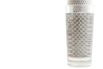 a glass cup filled with clean filtered water from the back of a charcoal filter for water...