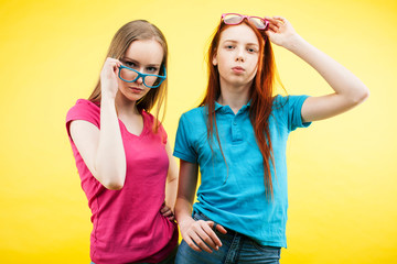 lifestyle people concept: two pretty young school teenage girls having fun happy smiling on yellow background wearing glasses