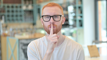 Naklejka premium Portrait of Young Redhead Man with Finger on Lips, Quiet