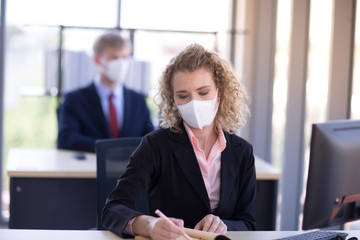 Business woman with curly blonde hair wearing a mask sitting in office, Concept,contagious disease, coronavirus, covid2019