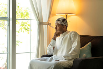  Middle Eastern, Emarati, Saudi, Moroccan man wearing a traditional kandura and prayer cap relaxed...