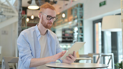 Naklejka na ściany i meble Attractive Redhead Man with Digital Tablet in Cafe