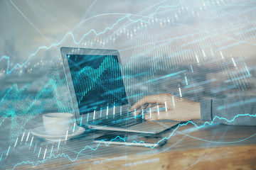 Double exposure of stock graph with businessman typing on computer in office on background. Concept...
