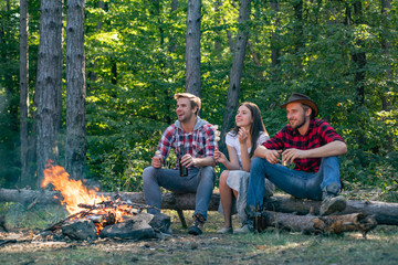 Happy young friends having picnic in the country. Company adult friends relaxing near campfire. Young couples having picnic in woods. Young people enjoying picnic in park on summer day.