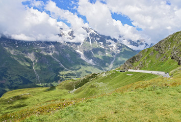 The Grossglockner High Alpine Road (in German Großglockner-Hochalpenstraße)  is the highest surfaced mountain pass road in Austria. Summer with  blue skyes green mountains and street for wallpaper.