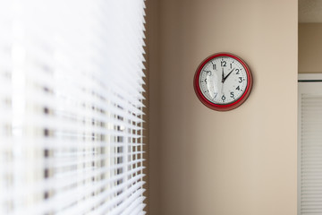 Red wall clock next to a window
