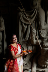 An young and beautiful Indian Bengali brunette woman in red white traditional ethnic sari holding a...