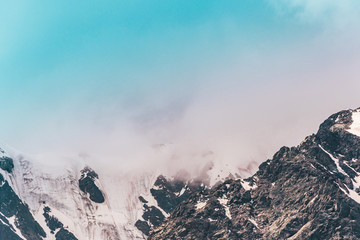 Mountain range under cloudy sky. Snowy peaks of mountains rocks