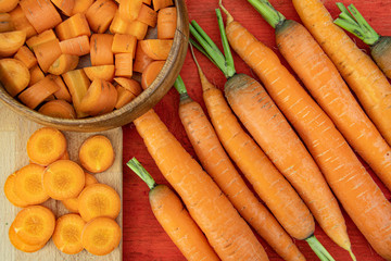 freshly cut carrot slices in plate on red wooden table, cooking vegetarian salad for healthy eating