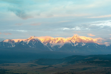 Fototapeta premium snow peaks on horizon, ridge of rocks under cloudy sky in mountain valley