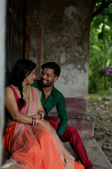 An young and attractive Indian Bengali brunette couple sharing romantic moments while sitting on the staircase of a vintage house wearing Indian traditional ethnic cloths. Indian lifestyle and fashion