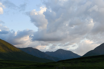 cumulus clouds over rock ridge, waiting for rain in mountain valley
