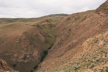 gentle red hills, journey through mountain valley, pastures for animals, soil erosion in arid steppe