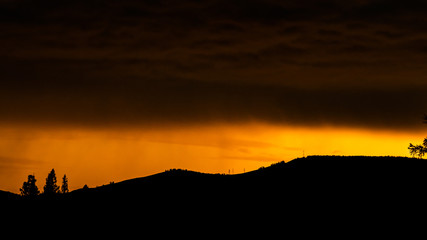 orange sunset and clouds over silhouette of mountain range