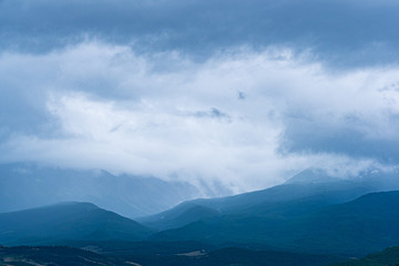 forest hills on horizon are covered with haze, mountain range in  distance in fog, reaching distant goal on way on foot