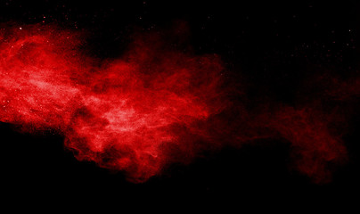 Red powder explosion on black background. Colored cloud. Colorful dust explode. Paint Holi.