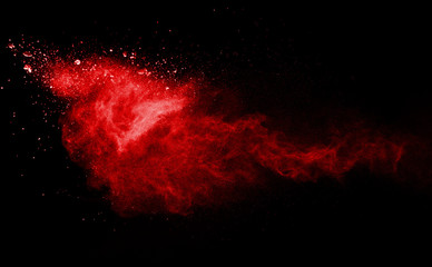 Red powder explosion on black background. Colored cloud. Colorful dust explode. Paint Holi.