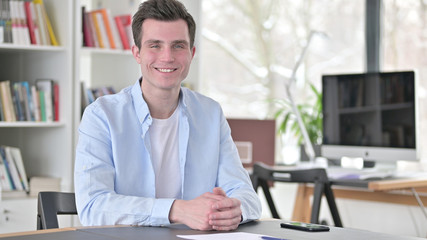 Fototapeta na wymiar Smiling Young Man in Office Looking at Camera
