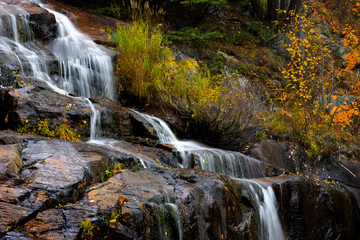 Fototapeta na wymiar Small water falls by highway 155 in Quebec province during autumn time
