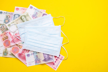 Chinese banknote (Yuan) and new white mask on yellow. .Mask is important but lack and very expensive in many country of Virus situation in 2020