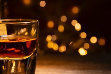 Glasses of whiskey place on wooden table. Vintage countertop with highlight and yellow bokeh from small light bulb 