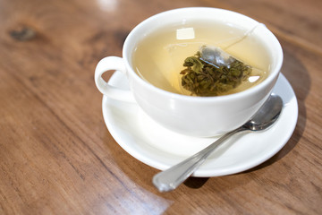 Hot green tea with tea bag in white cup