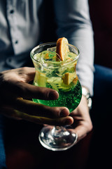 hands holding green cocktail