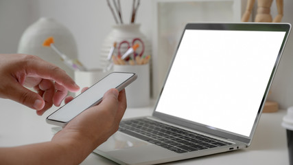 Cropped shot of artist using blank screen smartphone with working with blank screen laptop and painting tools