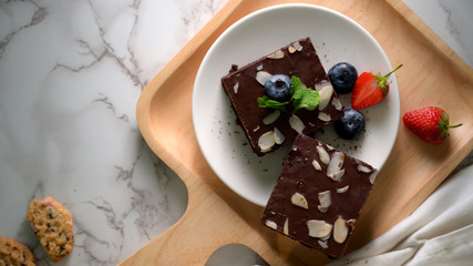 Top view of chocolate brownies on white plate with mint leaf on top