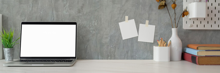 Cropped shot of modern workplace with mock-up laptop ,copy space, stationery and decorations