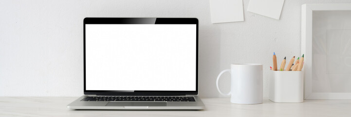 Cropped shot of workspace with blank screen laptop, white mug, stationery and decorations on white...