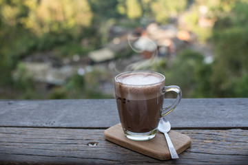 Coffee cup on the wooden table with nature landscape background.