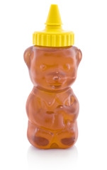 Honey in plastic dose, which is shaped like small bear. Isolated on white background with shadow reflection. With clipping path. With vector path. Copper in plastic bear shaped container, on white bg.