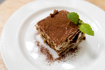 A plate of Tiramisu cake with fresh mint leaf 
