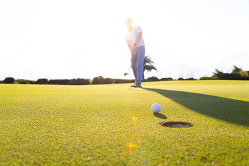 Golf club and ball in grass at the Golf course. White Golf ball on Green field golf course in...
