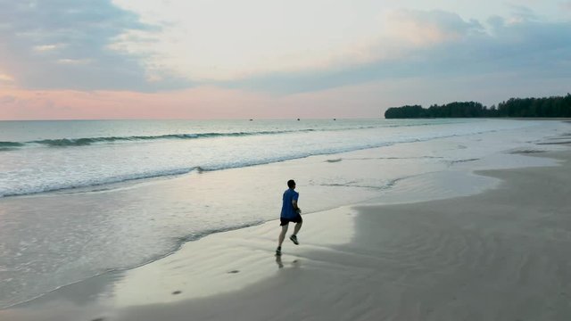 Silhouette video of a single male runner on a tropical beach at sunset
