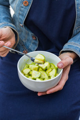 Green fresh zucchini slices salad in woman hands. Vegan vegetarian healthy diet