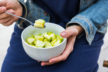 Green fresh zucchini slices salad in woman hands. Vegan vegetarian healthy diet