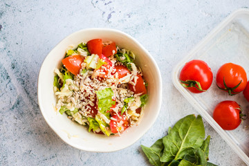 Fresh summer salad with tomatoes, green leaves, dressed with sesame and sunflower seeds topping.