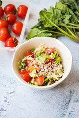 Fresh summer salad with tomatoes, green leaves, dressed with sesame and sunflower seeds topping.