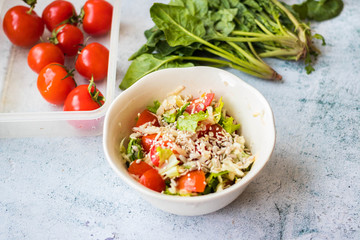 Fresh summer salad with tomatoes, green leaves, dressed with sesame and sunflower seeds topping.