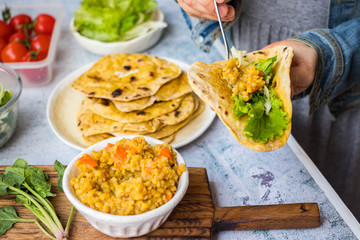 Chapati Indian flatbread. Traditional round bread. Fresh green salad and red dal lentil stuffed naan. Vegan, vegetarian healthy food. Hands make vegetable wrap